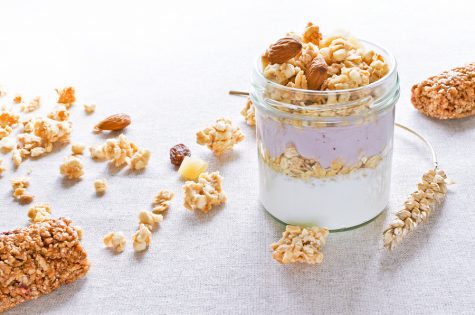 Greek yogurt with fruit crunchy muesli bars wheat cones linen background healthy breakfast concept