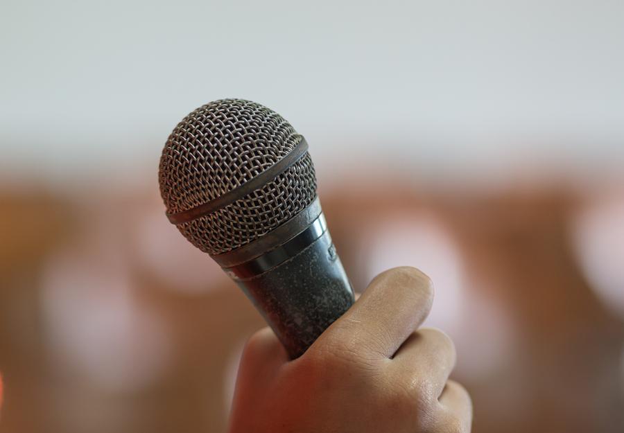 blurred of hands holding businesspeople speech and speaking with microphones in seminar talking conference hall light with microphones and keynote. Speech is vocalized form of communication humans.