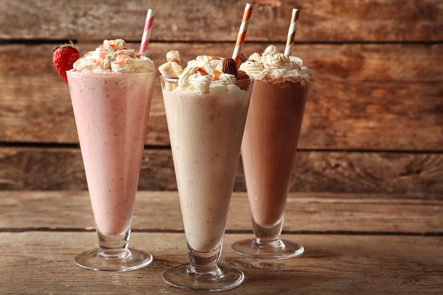 Delicious milkshakes on wooden background