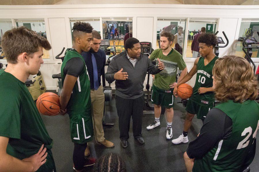 Assistant Athletic Director Tom Nelson, who also teaches math and coaches Varsity 1 basketball, chats with his players at halftime. Photo by David Barron.  