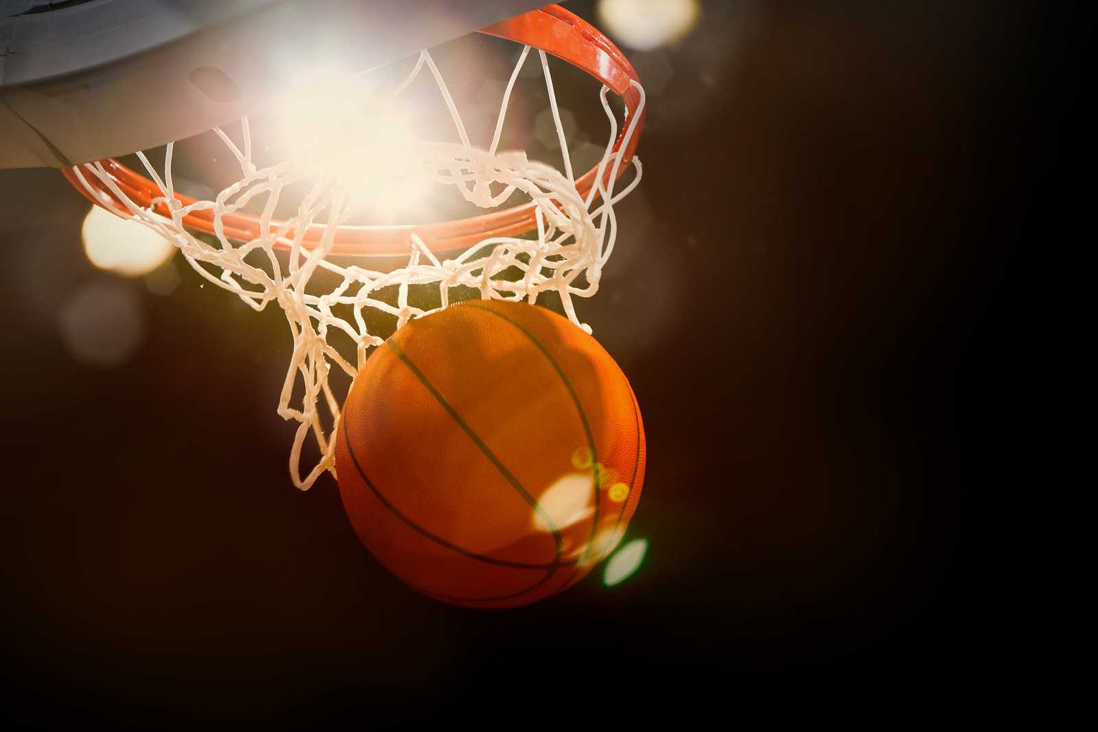 Basketball going through the basket at a sports arena (intention