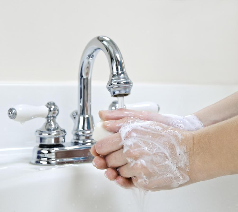 Child washing hands with soap under running water