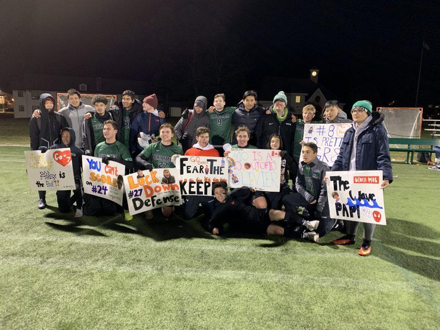 The team celebrates after its victory against Gann Academy, while also showing off fan signs. Photo by Dr. Nathalie Boileau