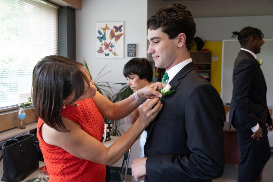 Director of Development Elizabeth Smith pins a boutonnière for James Yfantopulos 22 before last years commencement. 
