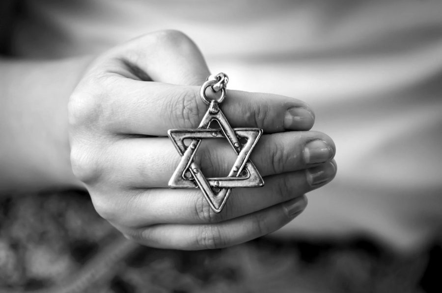 A person holds the Jewish Star of David, a symbol of the faith. 