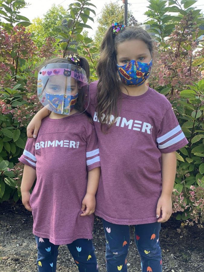 Sister campers pose in masks on campus.