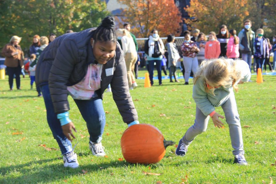 Middle and Lower School buddies help each other during the pumpkin rolling contest.