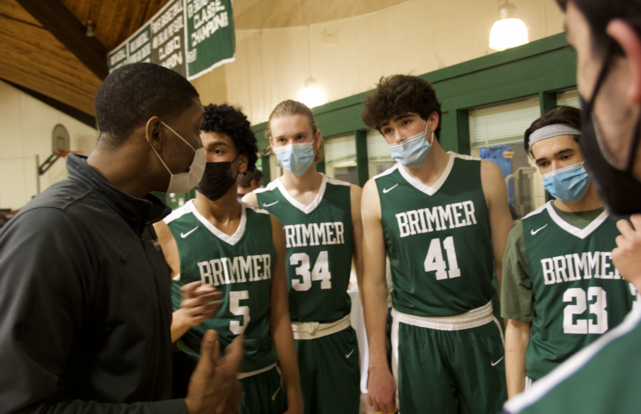 Basketball players Raymond Baez 24, Jackson Ostrowski 22, Theo Johnson 22, and David Kaplansky 22, huddle with their coaches during timeout.