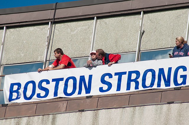 Fans unfurl a Boston Strong banner during the 2013 Red Sox World Series Parade. Photo Courtesy of Wikimedia Commons.
