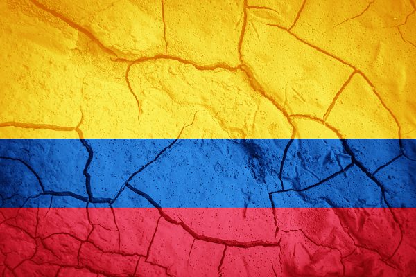 Colombian flag on the background of dry cracked earth.