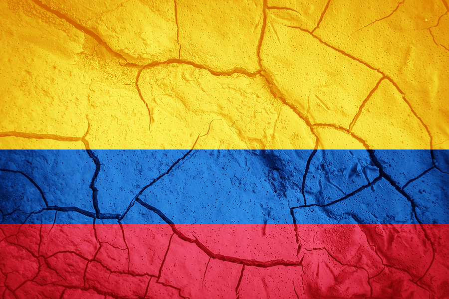 Colombian+flag+on+the+background+of+dry+cracked+earth.