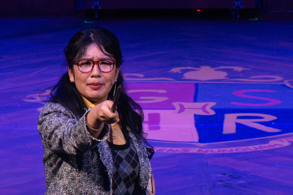 Mary Wang '26, as narrator, points to the audience.