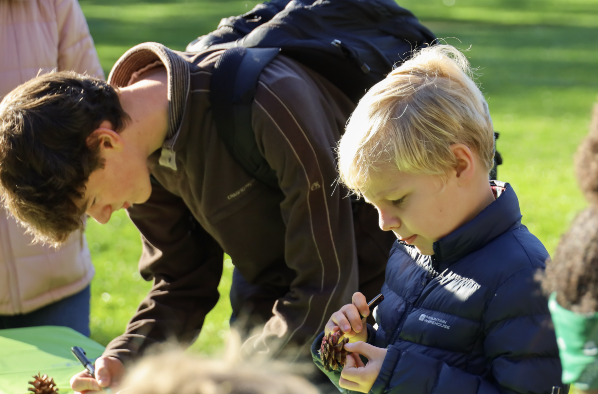Ben Weaver '29 does pine cone art beside a kindergarten student. 
